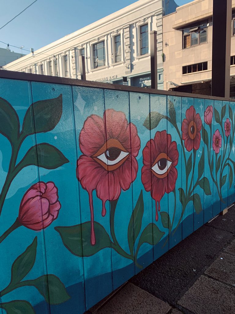 Fringe Bar exterior mural featuring large pink and red flowers on a blue background, hand-painted by Kate Helen Muir.