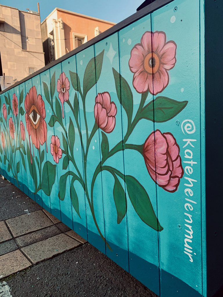 Fringe Bar exterior mural featuring large pink and red flowers on a blue background, hand-painted by Kate Helen Muir.